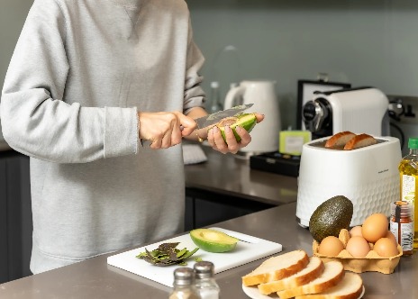 Person cutting a avocado in Dao by Dorsett room kitchenette.